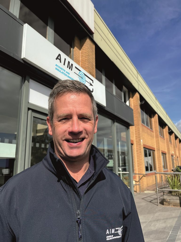 Images shows Phil Reynolds standing before the main entrance to AIM Ltd