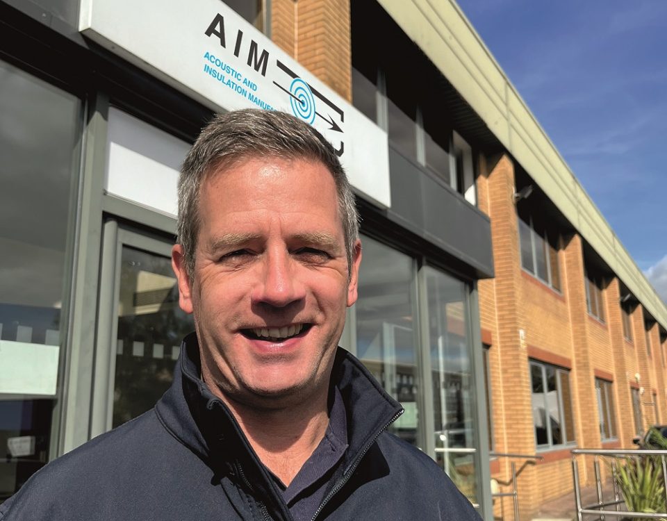 Images shows Phil Reynolds standing before the main entrance to AIM Ltd